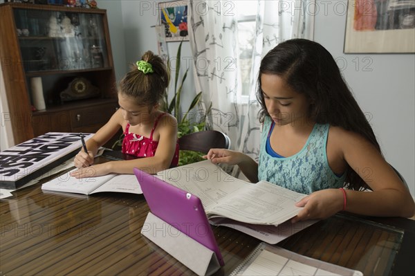 Mixed race sisters doing homework at table