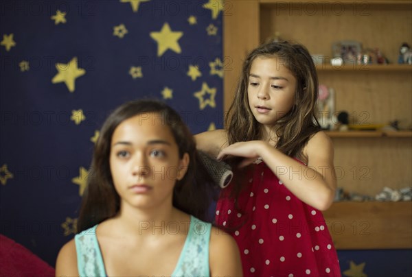 Mixed race girl brushing sister's hair