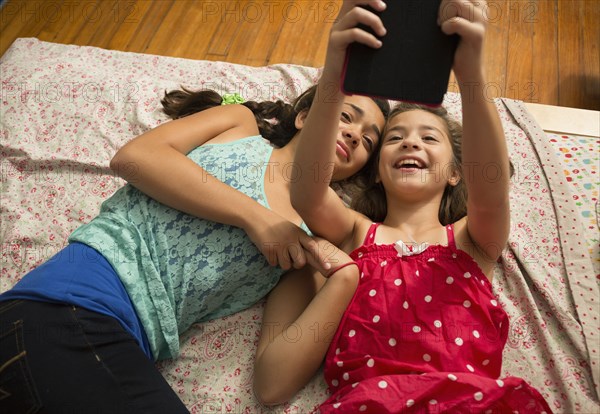 Mixed race sisters using digital tablet on bed