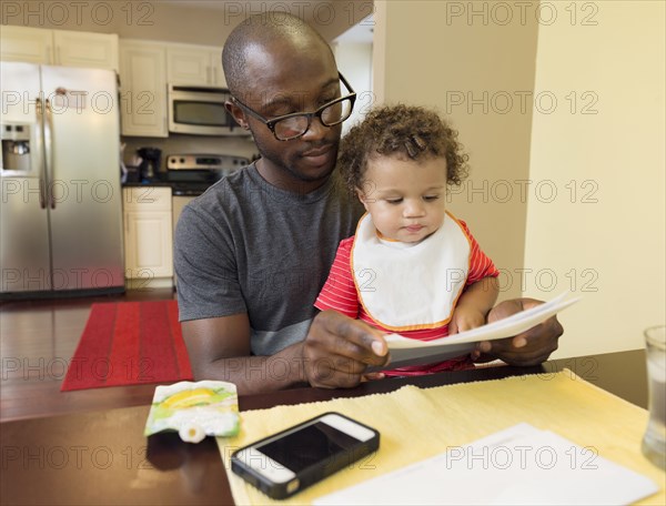 Father and toddler son sitting at table