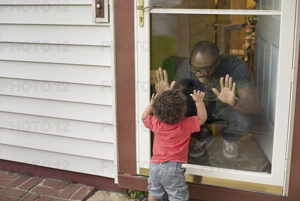 Father and toddler son playing at screen door