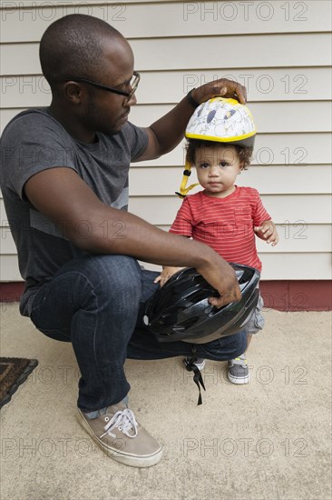 Father putting helmet on toddler son