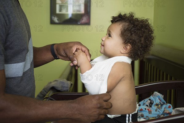 Father changing toddler son's clothes in nursery