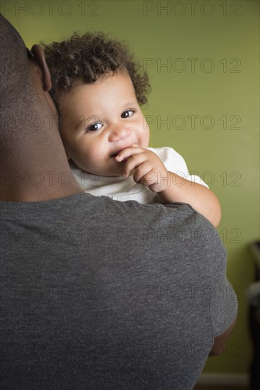 Father holding toddler son in bedroom