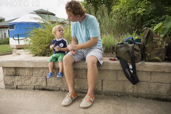 Caucasian father and toddler son sitting in park