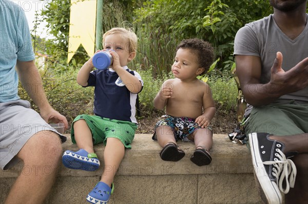 Fathers and toddler sons sitting together in park