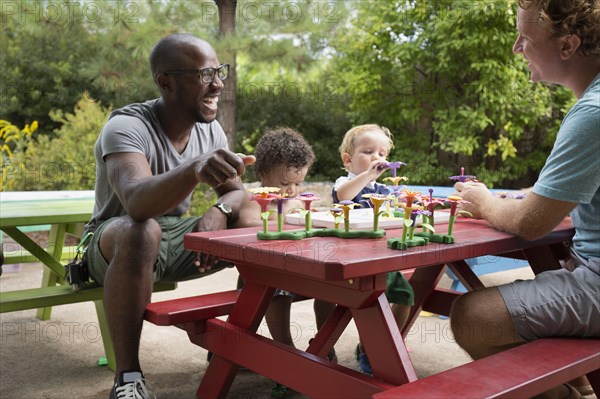 Fathers and toddler sons playing at picnic table