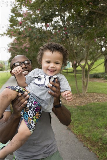 Father holding toddler son in park