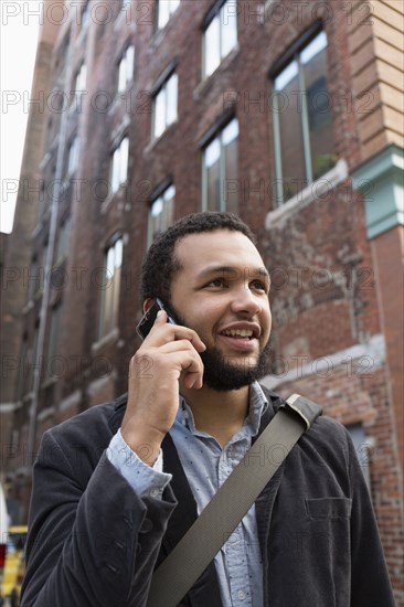 Mixed race businessman talking on cell phone in city