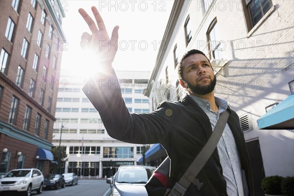 Mixed race businessman hailing taxi on city street