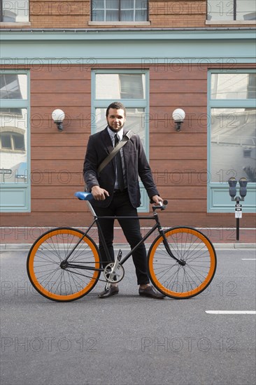 Mixed race businessman with bicycle on city street