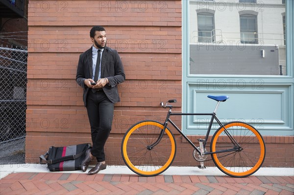 Mixed race businessman with bicycle on urban sidewalk