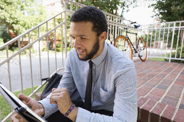 Mixed race businessman using digital tablet on front stoop