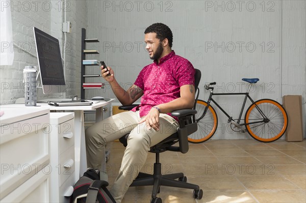 Mixed race businessman using cell phone at desk