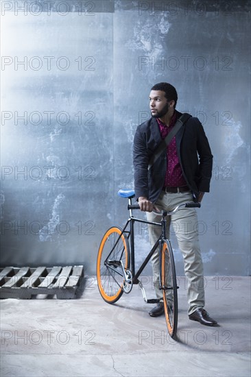 Mixed race businessman with bicycle in warehouse