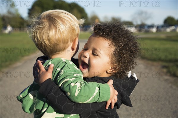 Happy baby boys hugging outdoors