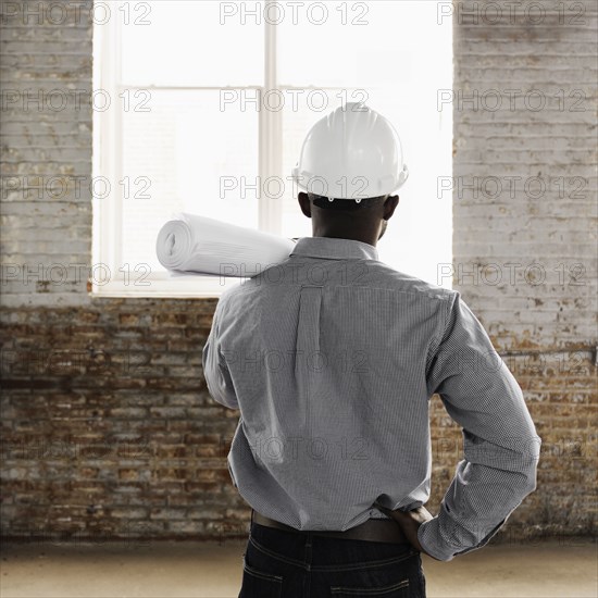 Black architect wearing hard-hat and holding blueprints