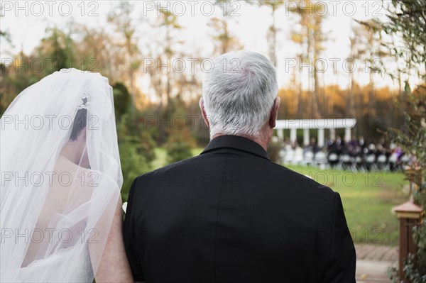 Caucasian father walking bride down aisle