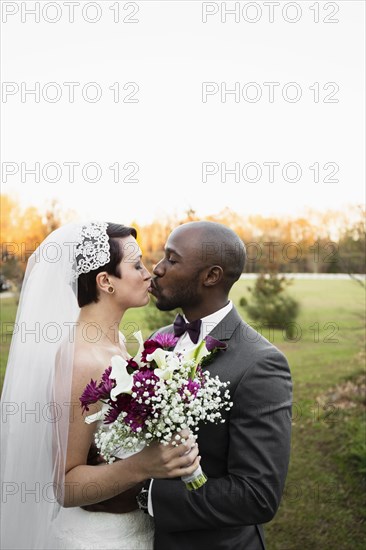 Newlywed couple kissing in park