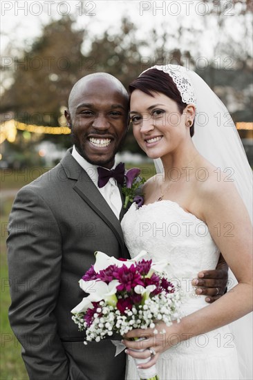 Newlywed couple hugging outdoors