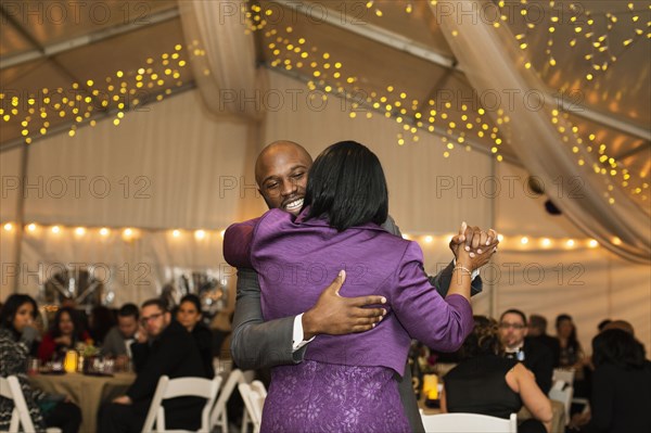 Black groom dancing with mother at reception