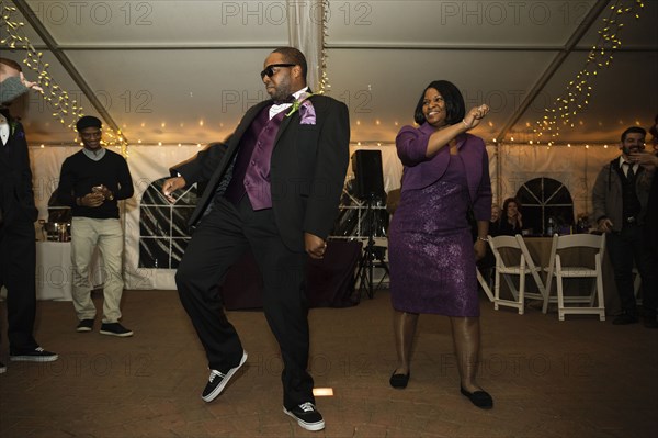 Black groom dancing with mother at reception