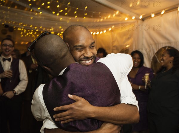 Groom hugging groomsman at reception