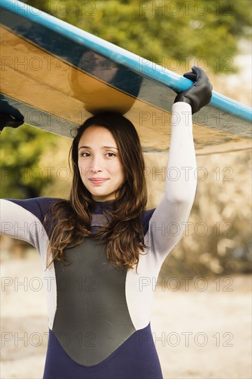 Hispanic surfer carrying board on beach