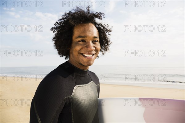 Mixed race surfer carrying board on beach
