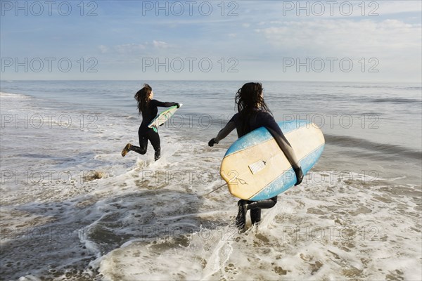 Surfers carrying boards in waves