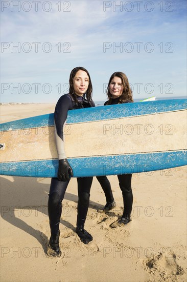 Surfers carrying boards on beach