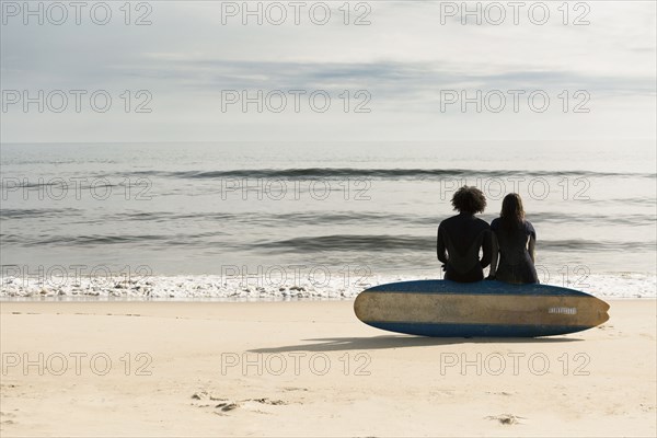 Surfers sitting on board on beach