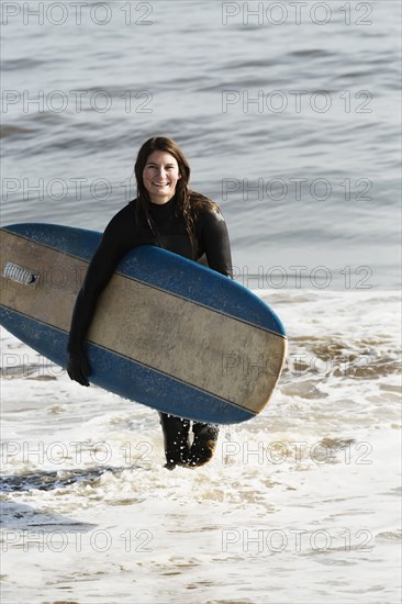 Caucasian surfer carrying board in waves