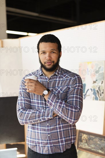 Mixed race artist drinking coffee in studio