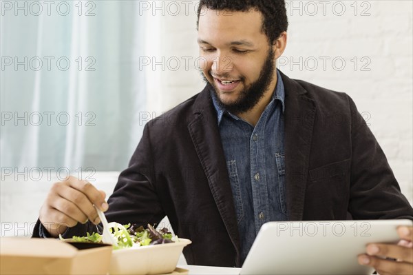 Mixed race businessman eating salad
