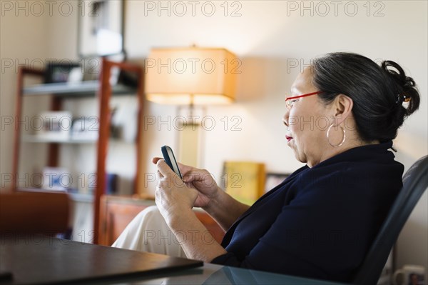 Japanese businesswoman using cell phone at desk