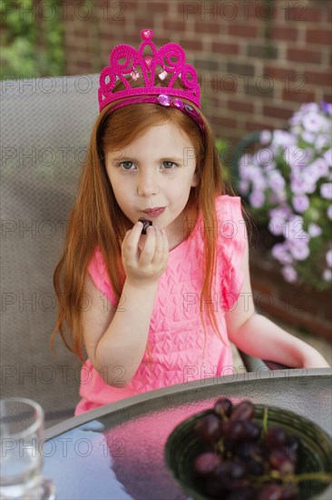 Caucasian girl eating fruit in backyard