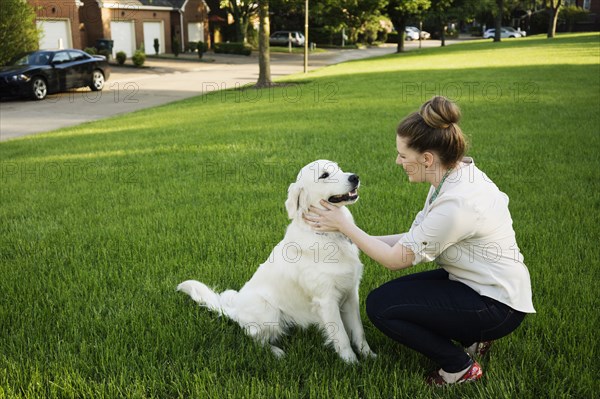 Caucasian woman petting dog in park