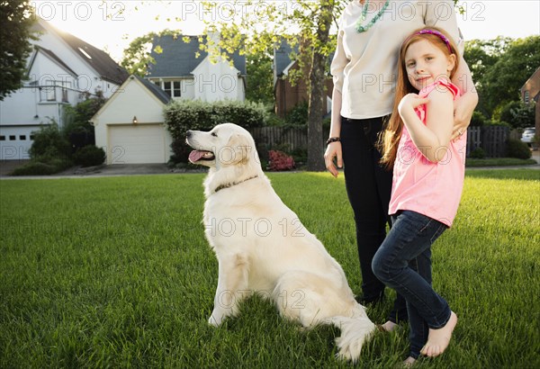 Caucasian mother and daughter with dog in park