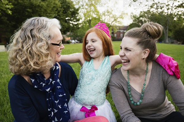 Three generations of Caucasian women sitting in park