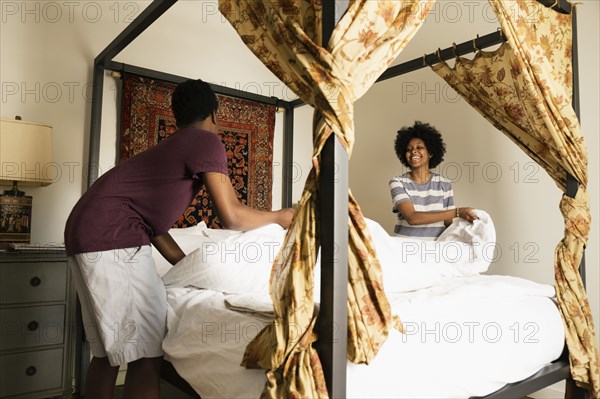 Couple making bed together