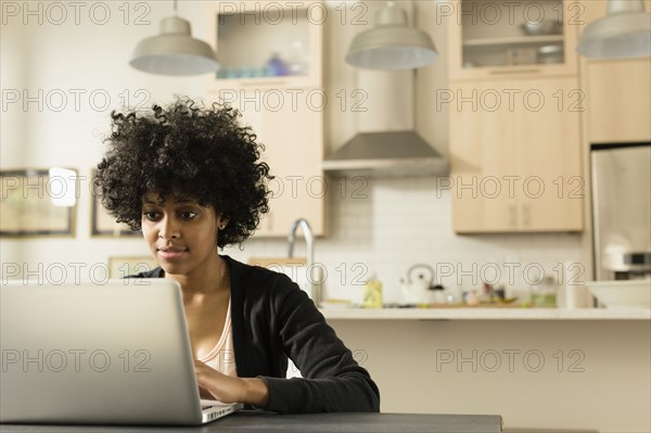 Mixed race woman using laptop at breakfast table