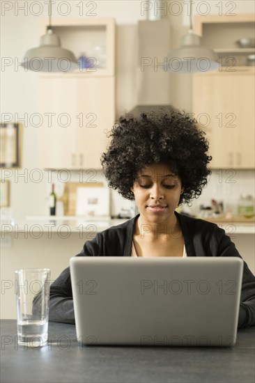 Mixed race woman using laptop at breakfast table