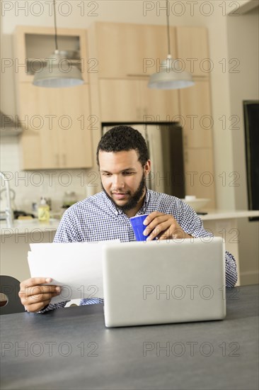 Mixed race man reading at breakfast table