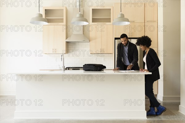 Mixed race couple reading paperwork in new house