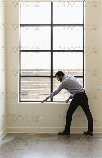 Mixed race realtor measuring window in new house