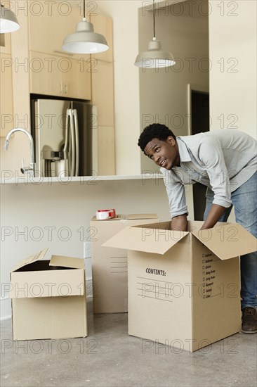 Black man unpacking cardboard box in new house