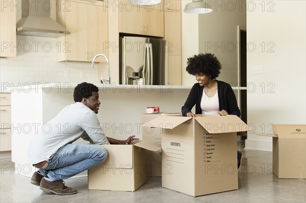 Couple unpacking cardboard box in new house
