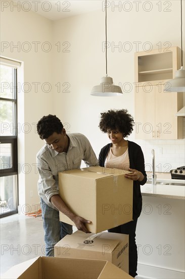 Couple hauling cardboard boxes in new house