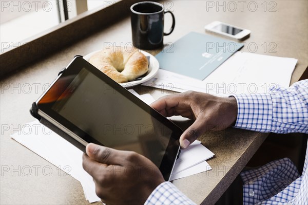 Black businessman using digital tablet in cafe